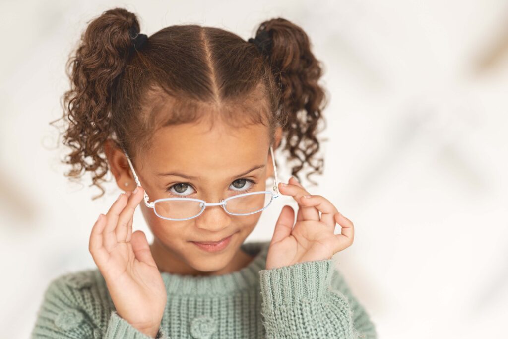 Little girl, glasses and vision portrait with a child wearing eyeglasses in eyewear store for eye care. Optometry, ophthalmology and cute female child posing with spectacles and lenses in retail shop.